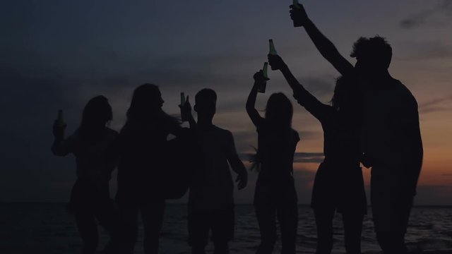 Group of friends finishing beach party. Man shaking beer bottle.