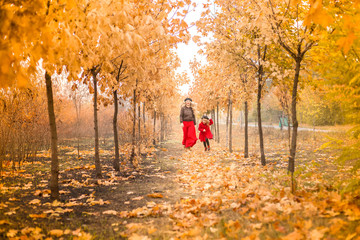 Fototapeta premium young mother plays with her little daughter in the autumn garden