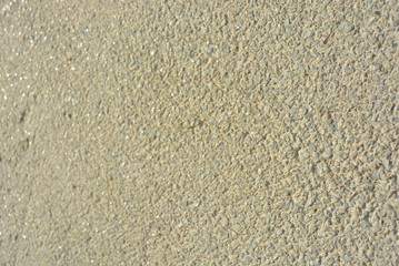 Yellow bright background, construction wall with very small glass stones matte white and gray with a reflection of the sun