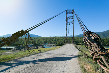 Tightened cables of the suspension bridge. A metal thick cable holding a bridge across a mountain river.