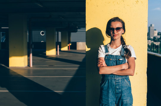 Girl in a jeans overalls looking straight in the parking