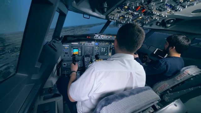 Airplane pilot instructor and a man are managing flight simulation process