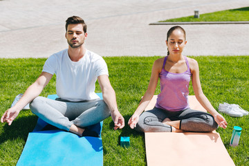 Inner peace. Pleasant young people sitting on the yoga mats while meditating