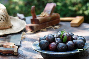 Summer plums and carpentry tools on the wooden table.