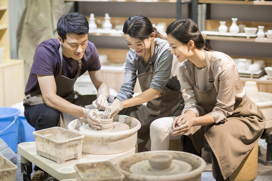Potter teaching young women making pottery