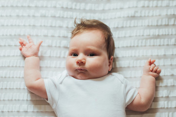 Fototapeta premium Cute infant child lying on white sheets 