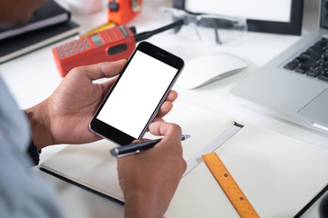 Man holding mockup smartphone on white table office workspace.