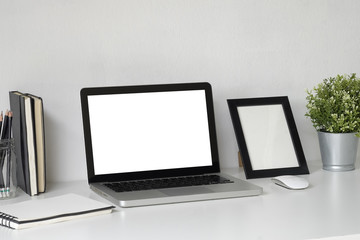 Mock up laptop computer on work space with photo frame, plat and jar of pencil copy space office table.