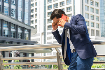 Serious worried businessman talking on red cell phone in the city. concept of Business failure and Sales decreased.