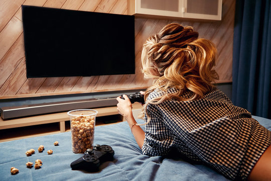 Girl in shirt playing video games lying on the bed