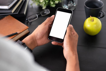 Man holding mockup smartphone on black table office workspace.