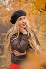 girl in a black beret with bright red lips against the backdrop of an autumn garden