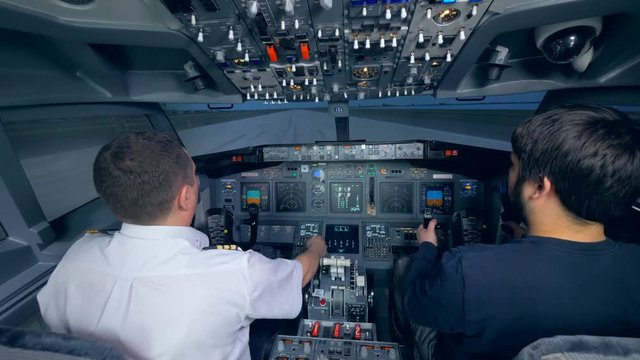 Two men are practicing landing in a flight simulation machine