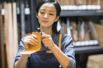 Young leather craftswoman working in studio 