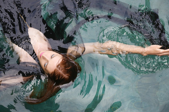 Fashion Photo Of Woman Wrapped In Black Sheer Fabric In Swimming Pool