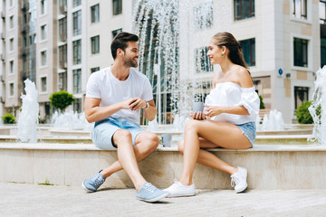 Fototapeta na wymiar Romantic date. Delighted joyful man smiling to his girlfriend while meeting her near the fountain