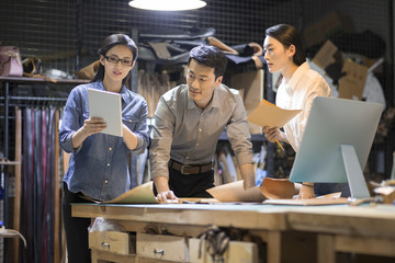 Confident leather craftspeople working in studio