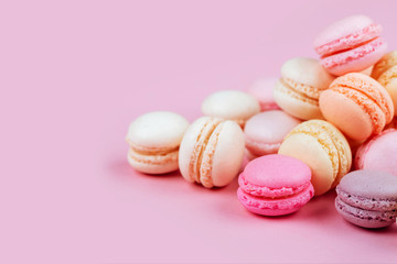 The row of colorful macarons on pink background.