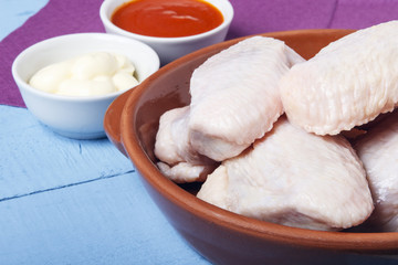 Fresh chicken wings of domestic bird in ceramic dishes for cooking a dietary dish. Space for design or text