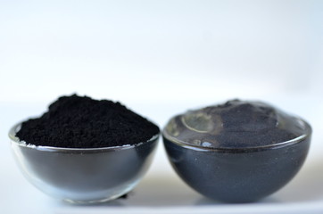 Cosmetic activated charcoal powder in a glass jar and beauty face mask mixture on white with copy space
