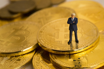 Fototapeta na wymiar Miniature figure a businessman stands on bitcoin coins currency.