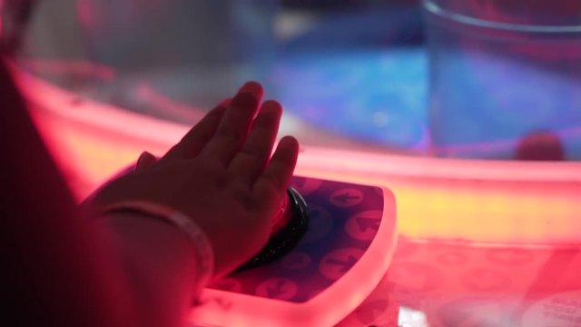 A slo-motion shot of a hand smashing a big red button on an arcade game.