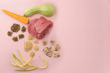 Natural raw ingredients for pet food on pink background.