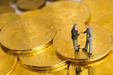 Fototapeta na wymiar Miniature figures of two businessmen agreed a deal on bitcoin coins currency.