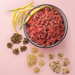 Natural raw ingredients for pet food on pink background.