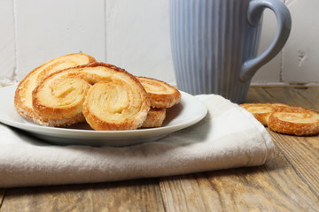 Spanish palmiers on a plate with a cup on wooden surface