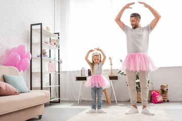 father and daughter in pink tutu skirts dancing like ballerinas