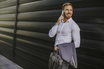 Fototapeta premium Happy smiling urban businessman using smart phone outside