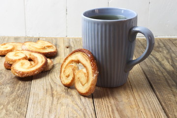 Spanish palmiers with a cup on wooden surface