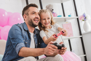 father and daughter having fun and playing with joysticks