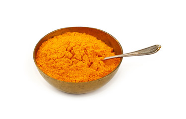 One bronze metal bowl full of yellow turmeric powder