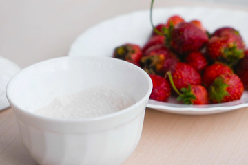 Juicy appetizing tasty strawberry on a white plate with sugar bowl.