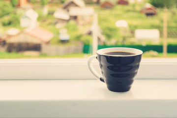 One cup of coffee for breakfast over white window sill with beautiful nature view, toned photo