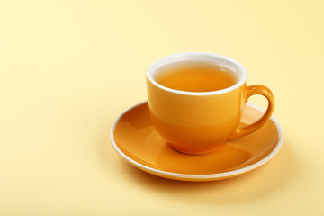 Yellow cup of green oolong tea on saucer
