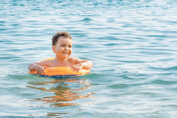 A happy child bathes in the sea on an inflatable circle