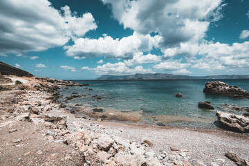 Panoramic view of rocks and beach with sky and clouds in Crete, Greece. Amazing scenery with crystal clear water and the rock formation against a deep blue sky during Summer period. Greece, Europe