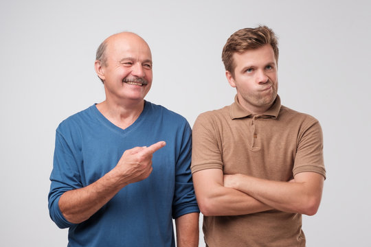 The elderly father laughs at his son. He won the argument. A young man is offended and discouraged by his loss.