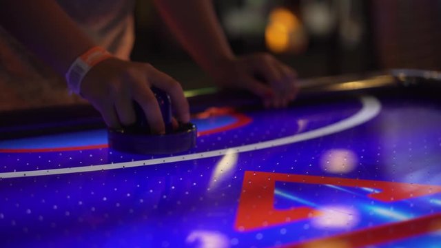 4K shot of an air hockey player hitting the hockey puck around and then letting the puck slip into the goal.