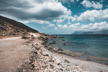 Panoramic view of rocks and beach with sky and clouds in Crete, Greece. Amazing scenery with crystal clear water and the rock formation against a deep blue sky during Summer period. Greece, Europe