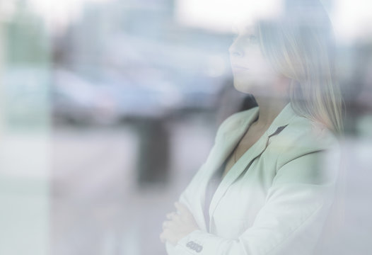 From Behind The Glass. Young Business Woman Looking Out The Office Window