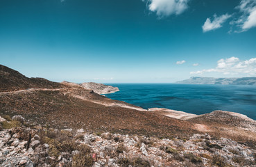 Panoramic view of rocks and beach with sky and clouds in Crete, Greece. Amazing scenery with crystal clear water and the rock formation against a deep blue sky during Summer period. Greece, Europe