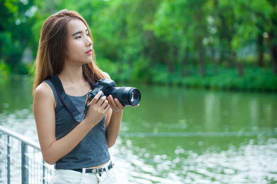 Young Asian woman photographer. beautiful girl with camera at summer green park taking pictures outdoors