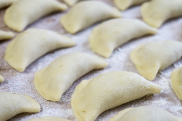 Traditional Russian food dumplings or vareniki, dough with meat or other stuffing, with flour and egg served on a table with sour cream, mushrooms and fresh vegetables, garlic sauce. traditional