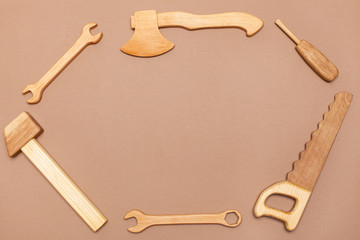 flat lay. A wooden hammer, a saw, a wrench, a screwdriver, an ax are toys for a boy. beige background with space for contextview from above on a wooden hand-made set with tools for the child