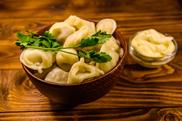 Fresh dumplings in ceramic bowl on wooden table