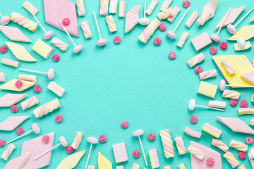 background, frame with marshmallows, sweets and lollipops on turquoise surface, copy space, top view